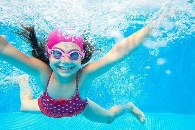 little girl deftly swim underwater in pool